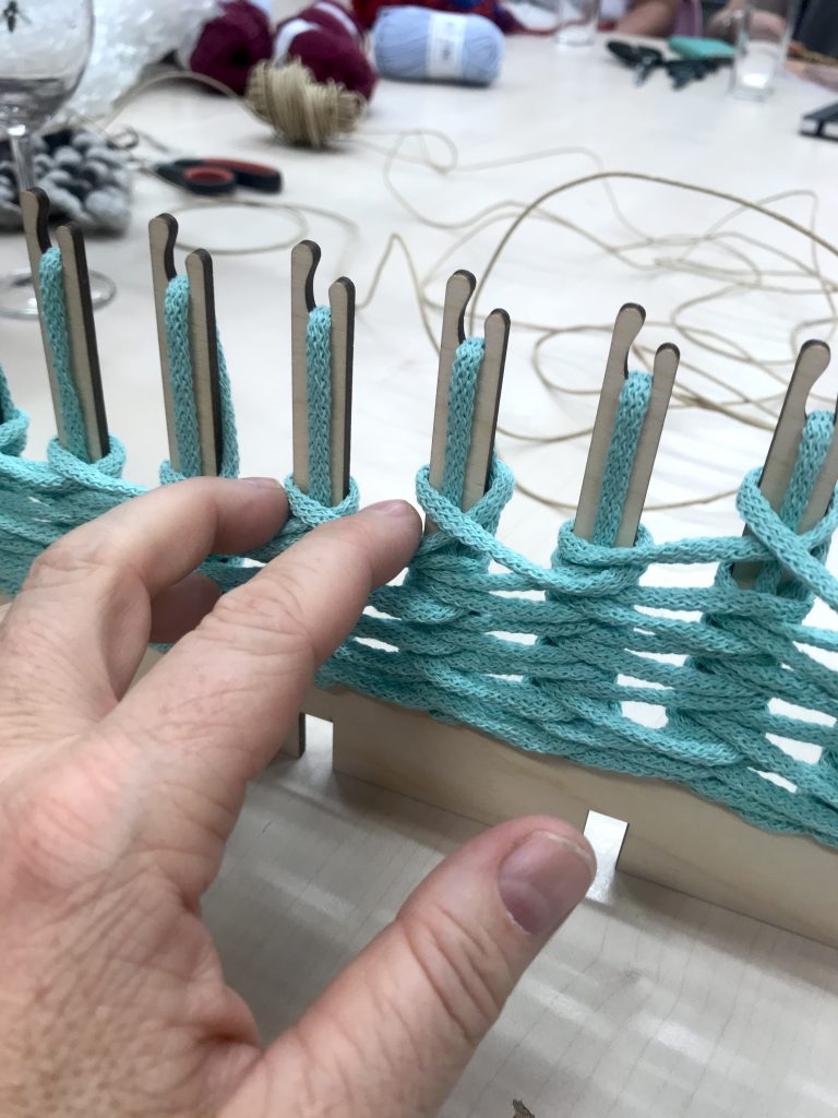 making a multi weave. En hand som gör loopar med en grön tråd